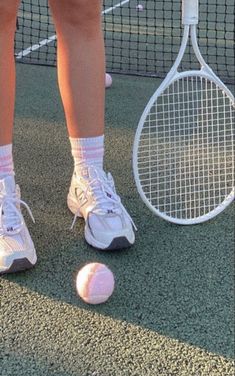 a person standing next to a tennis ball and racket