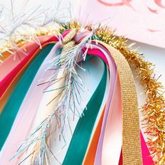 a bunch of ribbons that are next to each other on a white surface with gold, pink, and green streamers