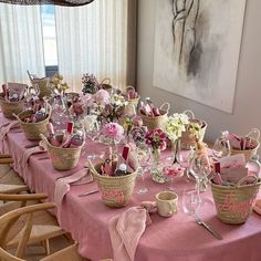 the table is set with pink linens and flowers in baskets on top of it