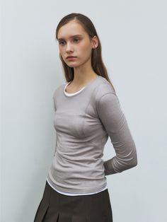 a young woman is posing in front of a white wall with her hands on her hips