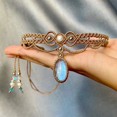 a woman's hand holding a gold bracelet with an opalite and pearls