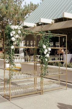 an outdoor bar set up with wine glasses and greenery