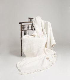 a white blanket sitting on top of a wooden chair