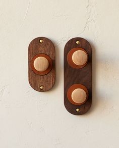 two wooden wall plaques mounted to the side of a white wall, one with wood circles