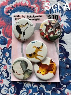 four buttons with animals on them sitting on top of a flowery cloth covered surface