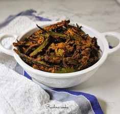 a white bowl filled with fried green beans on top of a blue and white towel