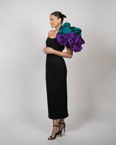 a woman in a black dress with purple and green ruffles on her shoulders