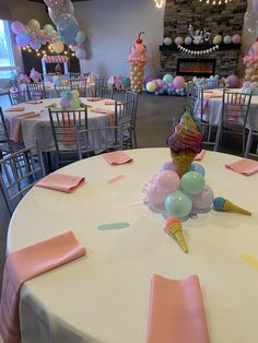 an ice cream cone sits on top of a round table surrounded by balloons and streamers