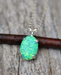 "A stunning necklace made using a very rare and hard to find opal color. This opal is a lovely shade of green with highlights of darker greens, yellows and even blues. The opal is set into a .925 Sterling Silver prong setting and hangs from Sterling Silver chain. Opal measures 14mm tall (3/8\") and is oval in shape. Pendant measures approximately 1\" long. Necklace closes with a sterling silver clasp. Please choose desired chain length at checkout. VERY LIMITED STOCK. What is a lab created opal? Green Opal Birthstone Jewelry, Opal Gemstone Necklace In Oval Cabochon Shape, Opal Gemstone Necklace With Oval Cabochon, Opal Oval Cabochon Gemstone Necklace, Green Opal Necklace For Gift, Opal Color, Birthstone Pendant, Green Opal, October Birthstone