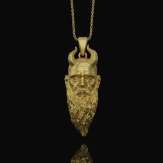 a gold necklace with an image of a man's head and horns on it