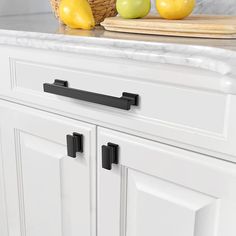 a kitchen with white cabinets and black handles