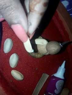 a person with pink nail polish on their nails and some seashells in a bowl