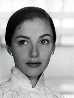 a black and white photo of a woman wearing a collared shirt with pearls on it