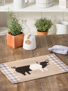 a dog rug sitting on top of a wooden table next to potted plants and kitchen utensils