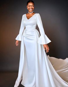 A luxury satin mermaid wedding dress. The dress features long sleeves and a fitted silhouette that flares out at the bottom. Simple Mermaid Wedding Dress, Detachable Skirt, White Wedding Gowns, Luxury Wear, Groomsmen Attire, Stunning Gowns, Mermaid Silhouette, Long Wedding Dresses, Dress Long Sleeve