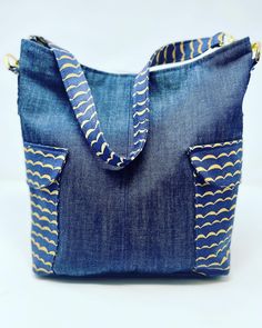 a denim bag with yellow and blue designs on the front, sitting on a white surface