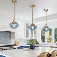 a kitchen with three lights hanging from the ceiling and two chairs on the counter top