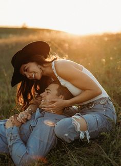 a man and woman sitting on the ground in a field with sun shining through them