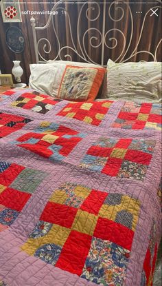 a bed with a quilt on top of it and an iron headboard in the background