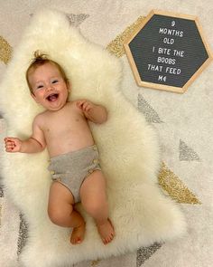 a baby laying on top of a white rug