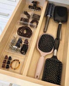 an open drawer with various hair brushes and accessories in it on top of marble countertops