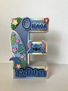 the letter e is decorated with lillies and flowers, including an image of a cartoon character