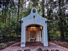 a small shrine in the middle of a forest with rocks and trees around it, surrounded by greenery