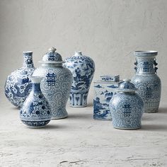 several blue and white vases sitting next to each other on a table with a wall in the background