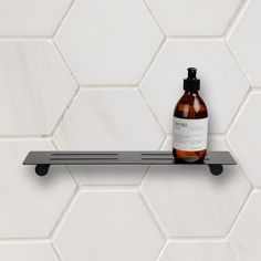 a bottle of lotion sitting on top of a shelf next to a white tiled wall