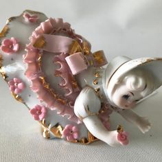 a porcelain figurine with pink flowers on it's body and arms, sitting on top of a plate