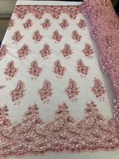 a pink and white table cloth on top of a bed