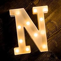 the letter n is lit up with lights on it's sides and sits in front of a wooden background