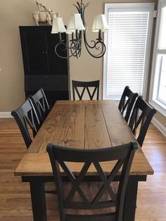 a dining room table with black chairs and a chandelier