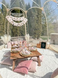 a table set up for a birthday party with pink and white decorations on the tables