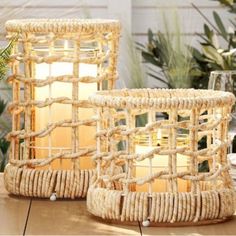 two wicker baskets sitting on top of a table next to each other with candles in them