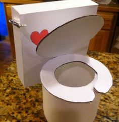 an open toilet paper box with a heart on the lid sitting on top of a counter