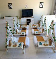 a room filled with white couches and tables covered in green plants next to a flat screen tv