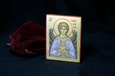 a small wooden box with an image of the virgin mary on it and a red velvet bag