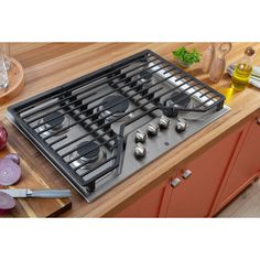 an image of a stove top with utensils on the burner and cutting board next to it