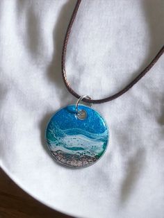 a necklace with a blue and white painting on it