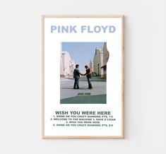 a pink floyd poster hanging on the wall next to a wooden frame with an image of two men shaking hands