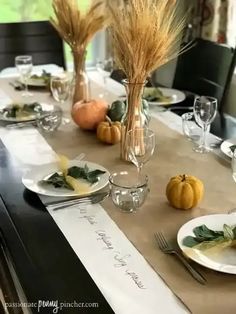 the table is set for thanksgiving dinner with pumpkins and gourds in vases