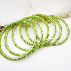 Introducing Cascade - Glass Bangles, featuring a stunning combination of lime green and soft gold. This bold and elegant accessory adds a pop of color to any outfit. Made with high-quality glass, these bangles are lightweight and comfortable to wear. Elevate your style with Cascade - Glass Bangles. *Sold as a six-piece set.*To prevent any potential damage, please put on each glass bangle individually. For a snug fit, we suggest sizing up from your usual bangle size. Elegant Green Bangle For Festive Occasions, Green Beaded Bracelets For Festive Occasions, Green Round Bracelets For Party, Adjustable Green Bangle For Party, Green Bohemian Bangle For Parties, Elegant Green Bracelets For Festive Occasions, Bohemian Green Bracelets For Festive Occasions, Adjustable Green Round Bangle, Adjustable Green Bangle