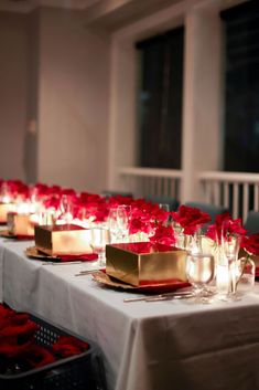 the table is set with candles and red flowers in vases on each side of the tables