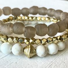 "This beautiful neutral beachy stack has just the right amount of sparkle and style and is the definition of beach chic! Neutral enough to wear with anything, classy enough to dress up and casual enough to wear anywhere! This trio is made with a 9mm sandy taupe 'sea glass' bracelet (from our very popular midi & chunky Sea Glass lines), 4mm faceted gold bracelet and 8mm white and tan magnesite gemstone bracelet.  Our Golden Sands stack would make a gorgeous wedding festivities look! It is a perfectly beachy~boho~neutral and would make a great gift too.   *Approximate length 7.25 inches (for an average 6.5-7\" wrist). Make a note in checkout to size up or down if preferred. *Comes gift-giving-ready with a Salty Sunshine branded tag, crinkle paper and a seafoam draw string bag. *Free shipping Elegant Adjustable Beaded Bracelets For Vacation, Elegant Stackable Beach Jewelry, Elegant Adjustable Beaded Bracelet For Vacation, Gold Stackable Beach Jewelry, Gold Stackable Jewelry For Beach, Gold Stackable Jewelry For The Beach, Elegant Adjustable Jewelry For Beach Season, Summer Gold Beaded Bracelets For Beach, Summer Beach Gold Beaded Bracelets