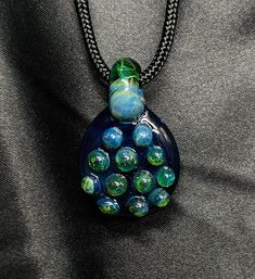 "Elevate your style with this unique Glass Pendant, meticulously crafted by me from premium Borosilicate glass. Each pendant is a wearable work of art, designed to make a statement and spark conversations. 🌟 Key Features: Material: Durable Borosilicate Glass Size: Approximately 1.5\" Included: Paracord.  ✨ Why Choose Borosilicate Glass? Kiln annealed borosilicate glass is known for its exceptional strength and resistance to temperature changes, ensuring your pendant stands the test of time. 🎁 Blue Cabochon Drop Jewelry, Blue Drop Cabochon Jewelry, Blue Drop Jewelry With Cabochon, Blue Teardrop Recycled Glass Jewelry, Blue Recycled Glass Round Jewelry, Blue Round Recycled Glass Jewelry, Handmade Blue-green Jewelry Gift, Unique Blue Drop-shape Jewelry, Unique Blue Drop Jewelry