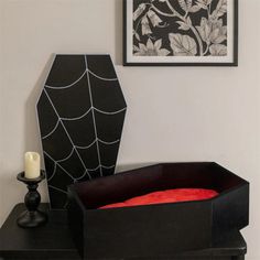 a black vase sitting on top of a table next to a spider web design box