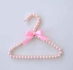 a pink tie with pearls on it and a bow at the end is attached to a white hanger