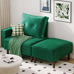 a green couch sitting next to a white table in a living room with pictures on the wall