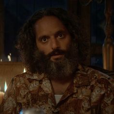 a man with long hair and beard sitting in front of candles